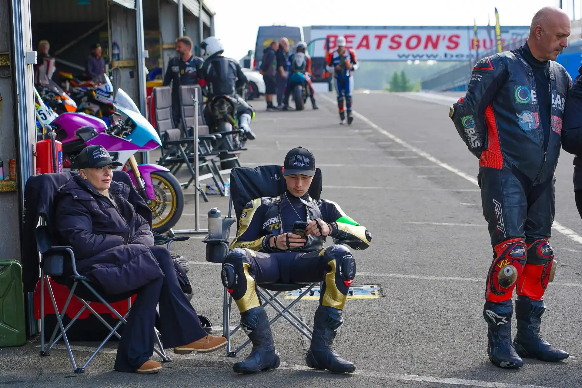 RND 7 Knockhill: The KTM Makes an Impression 4 Evan Brailsford seated in the Knockhill paddock in his racing leathers, checking his phone between sessions.