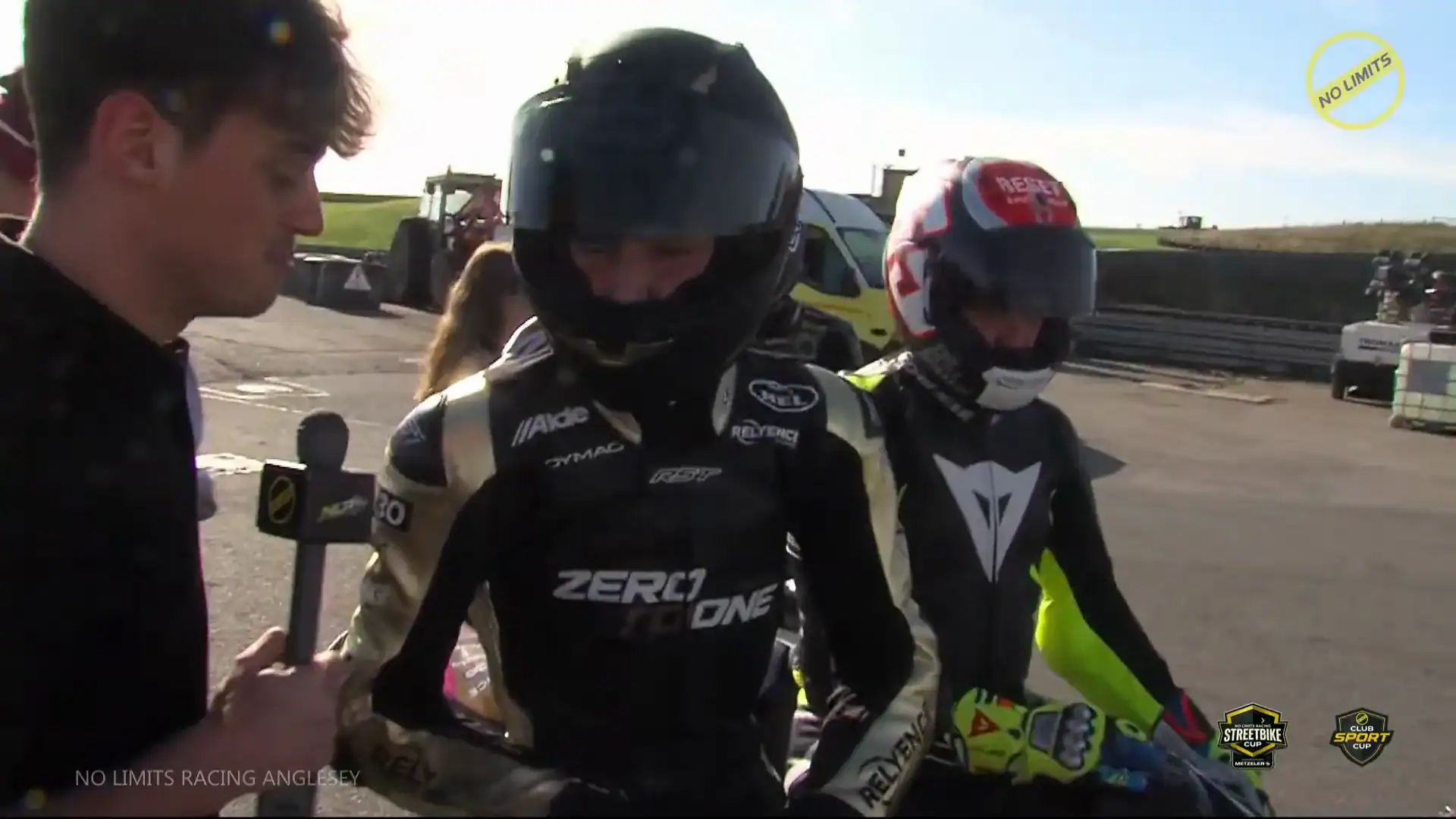 RND 8 Anglesey Coastal 6 NLR TV broadcast still of Evan Brailsford, helmet on and ZERO TO ONE across his leathers, being interviewed in Parc Fermé after Race 23 at Anglesey. Links to the interview on YouTube.